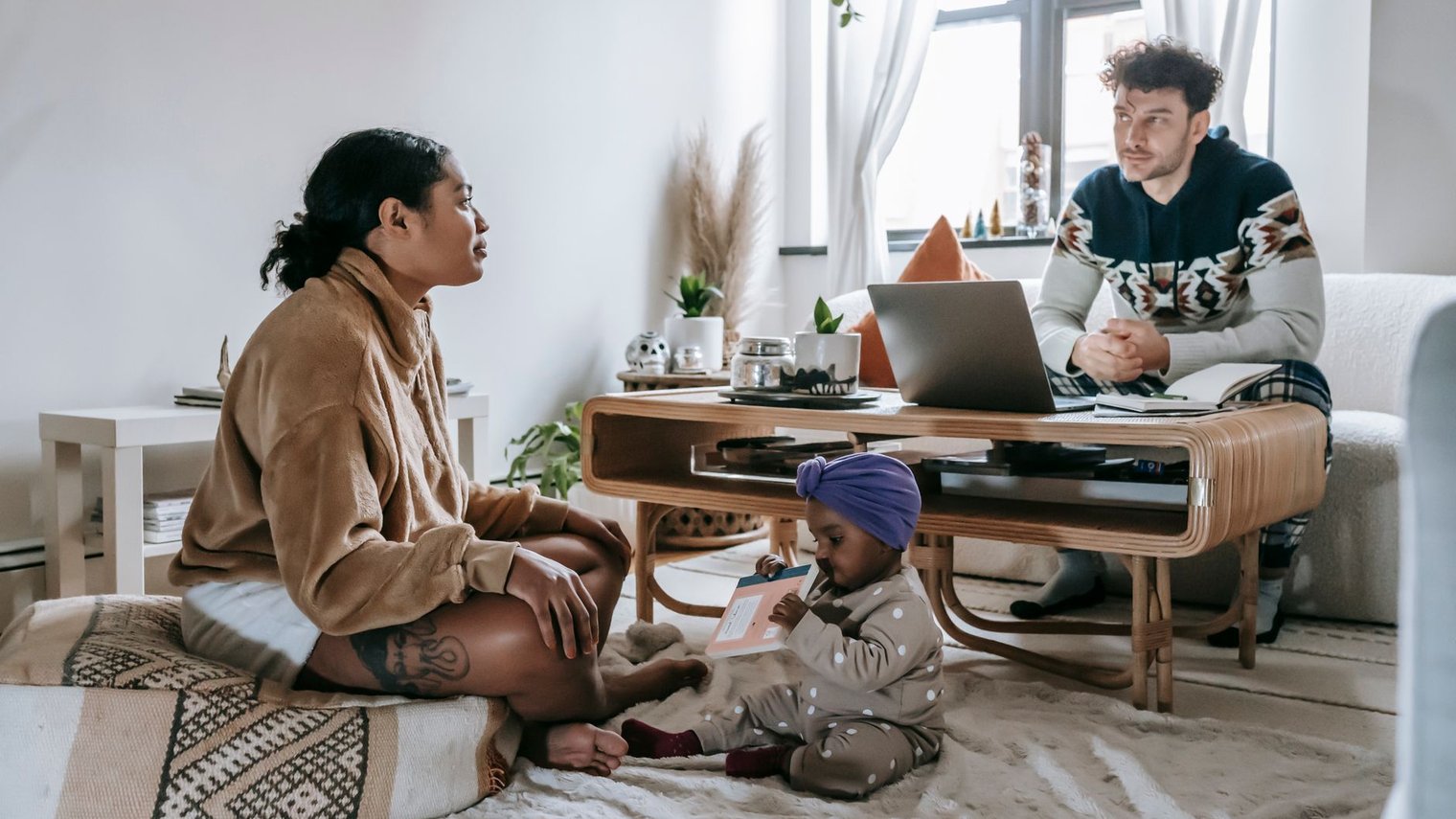 Familia en la sala de su casa con una computadora portátil, lista para una consulta en línea