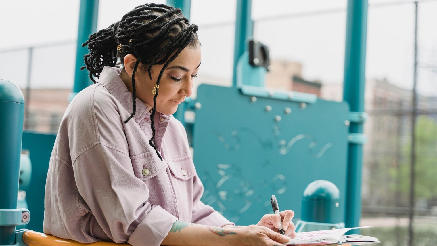 Mujer escribiendo en una libreta mientras revisa sus pensamientos al aire libre